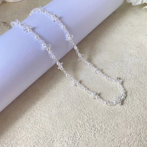 Detail of beaded necklace with white pearls and clear faceted crystals on a stand