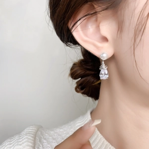 Détail de boucles d'oreilles élégantes en cristal et perle portées par un mannequin