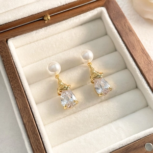 Vue macro des boucles d'oreilles goutte de cristal et perles dans un écrin de luxe