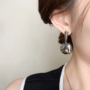 Polished silver teardrop earrings with a high-gloss finish worn on a model
