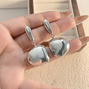 Detailed close-up of silver-tone polished drop earrings featuring smooth pebble pendants