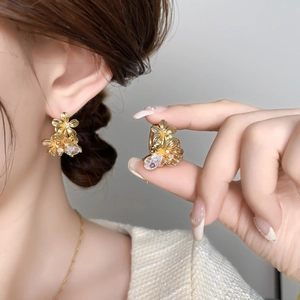 Boucles d'oreilles fleur dorées avec zircons et pendentif goutte portées sur modèle