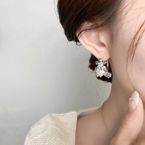 Gros plan de boucles d'oreilles fleurs en argent avec zircons portées par un modèle