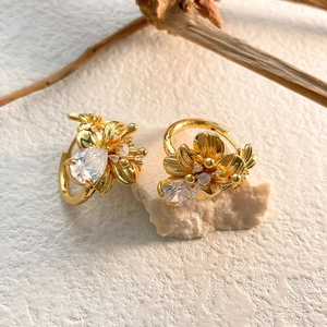 Gros plan sur boucles d'oreilles fleur dorées avec zircon goutte sur fond blanc