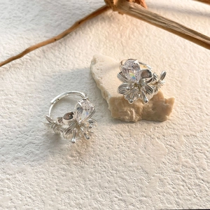 Détail de boucles d'oreilles fleur avec zircon poire sur fond de pierre et de bois