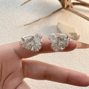 Détail des boucles d'oreilles fleurs en zircon avec pierres étincelantes sur la main