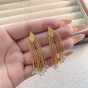Detail of gold tassel earrings with five bead chains and sparkling crystal drops