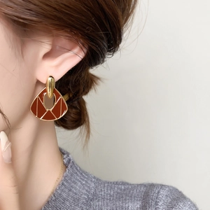 Close-up of vintage gold-tone heart earrings with deep red enamel on a model