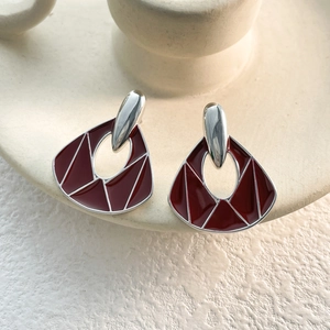 Detail of vintage silver earrings with deep red enamel and irregular geometric patterns
