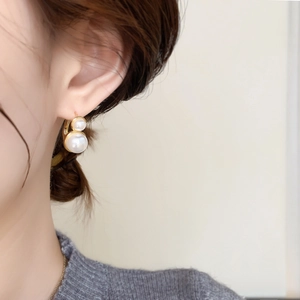 Macro shot of French vintage pearl earrings with gold finish on a model side profile