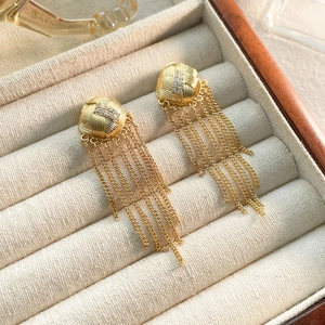 Gros plan de boucles d'oreilles dorées à pampilles avec globes tressés sur velours