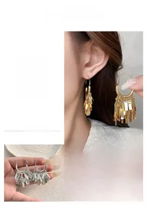 Close-up of dangling silver metallic tassel earrings with layered rectangular plates