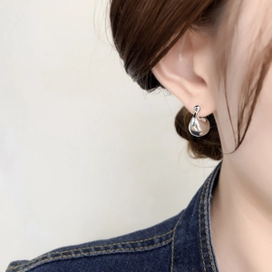 Minimalist silver teardrop earrings with high-gloss metallic finish worn by a model
