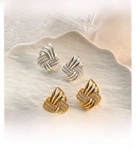 Macro detail of interwoven knotted earrings in gold and silver with zircon stones