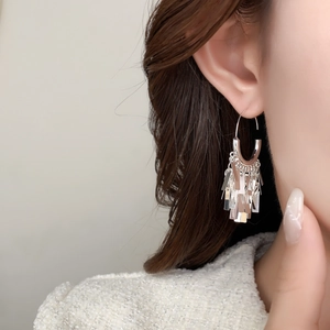 Close-up of silver tassel earrings with U-shaped hooks and tiered metallic sequins