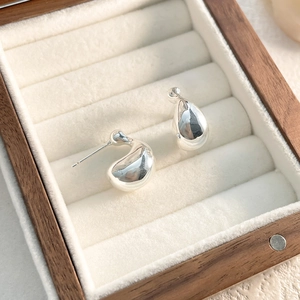 Macro shot of silver teardrop stud earrings with polished mirror finish in a jewelry box