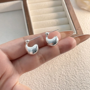 Detailed view of polished silver drop earrings with a modern minimalist C-shape design