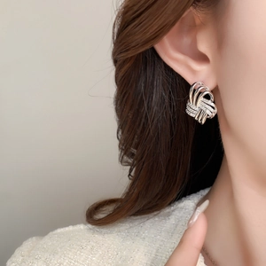 Elegant woven knot silver stud earrings with zirconia accents worn by model