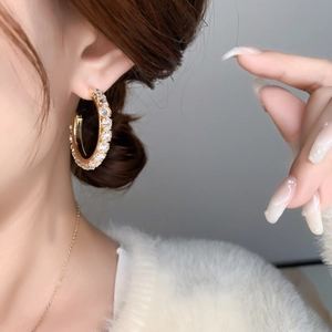 Detailed view of elegant gold hoop earrings with full zircon stones worn by a model