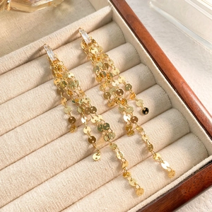 Détail macro de longues boucles d'oreilles dorées à pompons avec zircon sur velours