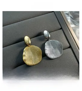 Macro view of gold and silver geometric earrings with radiant textures in a display box