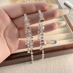 Détail de boucles d'oreilles longues à pampilles avec zircons et sequins brillants