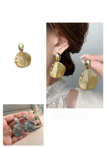 Detailed view of petal-shaped earrings in gold and silver finish with brushed texture