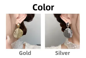Detailed view of large irregular pleated metal earrings in gold and silver finishes
