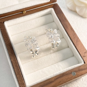 Gros plan de boucles d'oreilles en zircon en forme de C dans un écrin à bijoux en bois