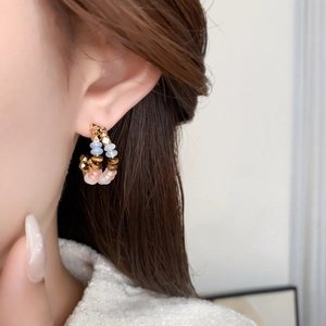 Détail d'une boucle d'oreille créole en C avec perles colorées et accents dorés sur l'oreille