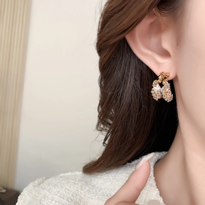 Gros plan de boucles d'oreilles fleurs dorées avec cristaux de zircon sur un mannequin