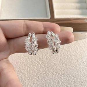 Détail macro de boucles d'oreilles créoles en C argentées ornées de zircons scintillants