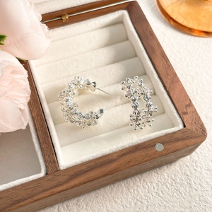 Detailed view of silver C-shaped stud earrings with unique crushed silver bead texture