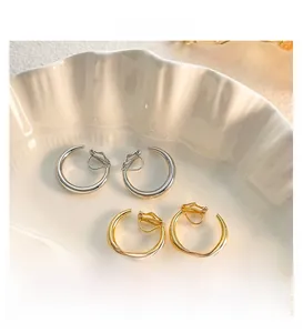 Nahaufnahme minimalistischer gold- und silberfarbener Creolen in einer weißen Schale