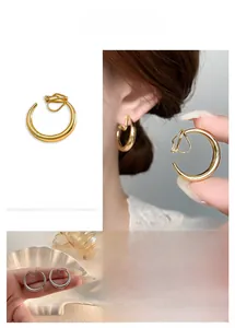 Detailansicht silberner und goldener C-förmiger Clip-Ohrringe im minimalistischen Stil