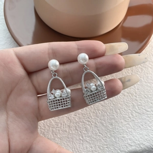 Close-up of pearl basket earrings with silver plating and shimmering crystal details
