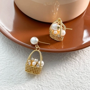 Detailed close-up of gold basket-shaped pearl earrings with sparkling zircons