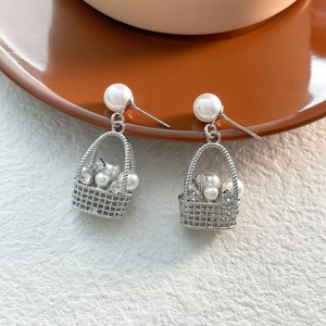 Detailed macro view of basket-shaped silver earrings with pearls and cubic zirconia