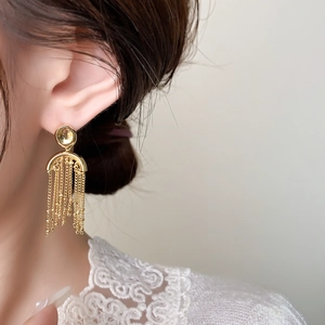 Nahaufnahme eleganter goldener Perlenketten-Quastenohrringe zu weißem Spitzenkleid