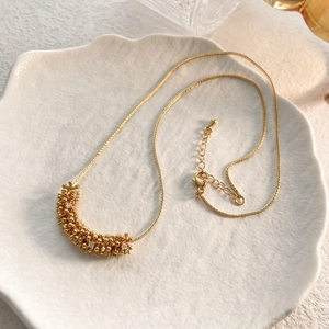 Detail of a gold clusters pendant necklace with zircons on a white ceramic plate