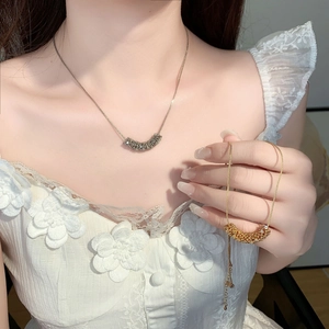 Close-up of a zircon necklace set in silver and gold tones on a white lace dress