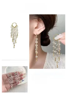 Detail of luxury fringe earrings with crystals and gold plating in ear buckle style