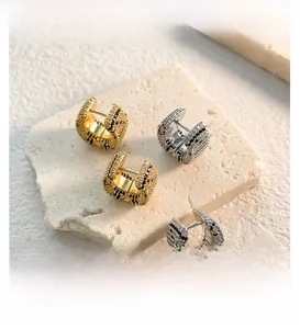 Macro view of C-shaped leopard print earrings with pavé zircons in gold and silver
