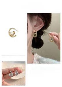 Detail of C-shaped spiral earrings with round cubic zirconia in 18K gold and silver finish
