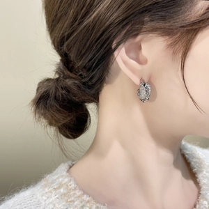 Detailed view of silver irregular spiral earrings with shimmering textured surface on a model