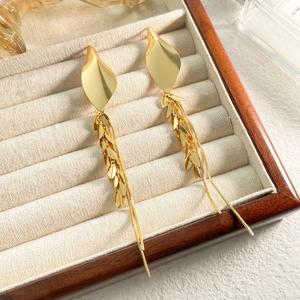 Detail of vintage gold tassel earrings with leaf motifs on a beige velvet jewelry box