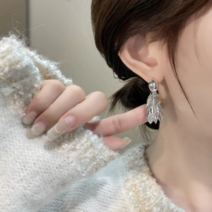 Élégantes boucles d'oreilles feuilles en or 18K avec zircons portées par un mannequin