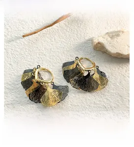 Detail view of retro ginkgo leaf earrings with gold and black textured finish