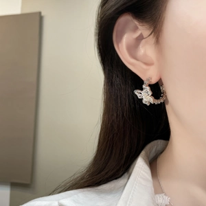 Detail of silver bow earrings with crystals and white pearls worn by a model