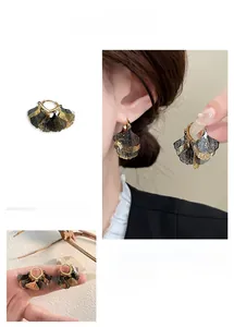 Detail of layered ginkgo leaf dangle earrings with gold and silver-black contrast design